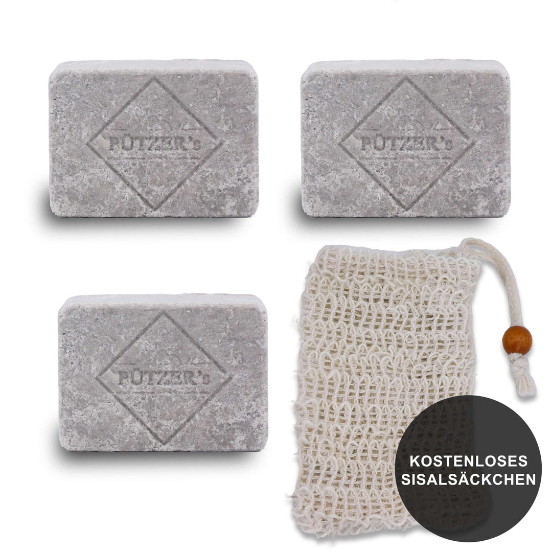 Drei rechteckige graue Seifenstücke mit der Prägung "PÜTZER's" und einem kostenlosen Sisal-Seifensäckchen mit Holzperle, auf weißem Hintergrund präsentiert.